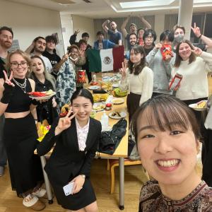 Students gather around a table and smile at the camera