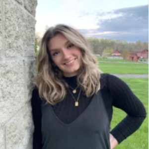 McKenzie Dominick poses for a photo leaning against a wall and smiling at the camera