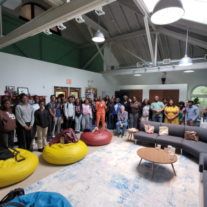Students and faculty gather in a room for a group photo.