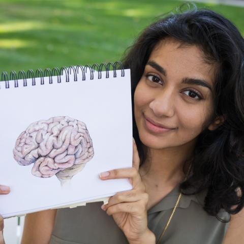 Sarrah Hussain holds up a drawing of a brain