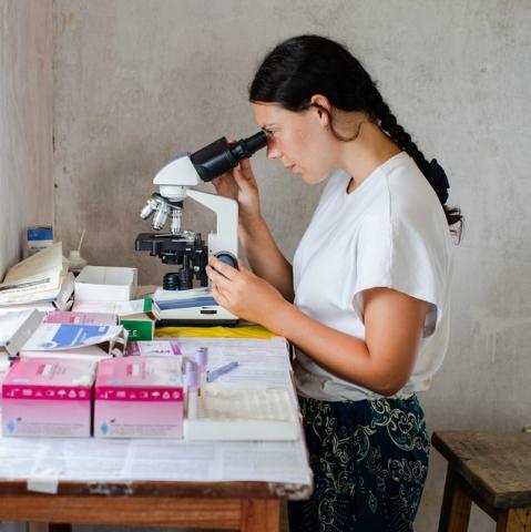 Willow Munson looks at a blood sample in a microscope from a patient who has been diagnosed with malaria. 