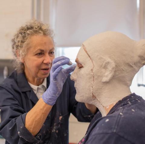 Lucy Gans puts plaster on a student's head and face