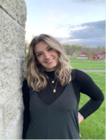 McKenzie Dominick poses for a photo leaning against a wall and smiling at the camera