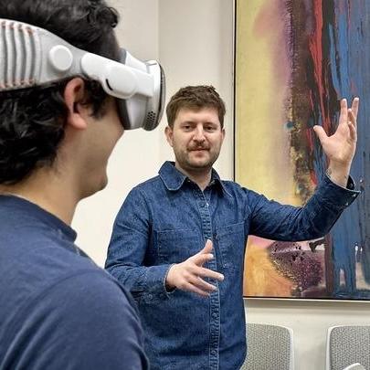 Joseph Amodei stands with a student who wears VR goggles.
