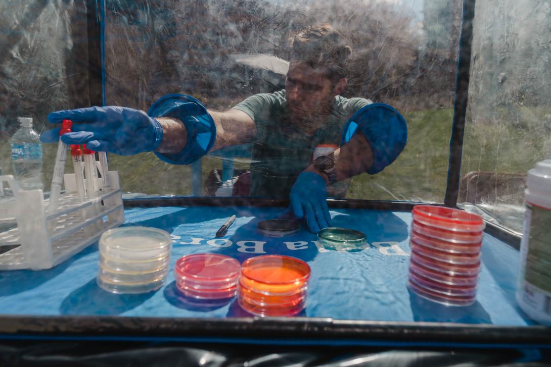 Lorenzo Servitje puts vials in a holder. His hands are in a protective tent and he wears gloves.