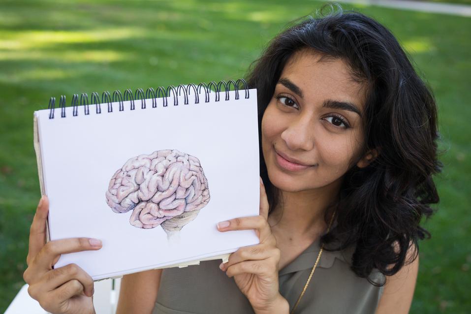 Sarrah Hussain holds up a drawing of a brain