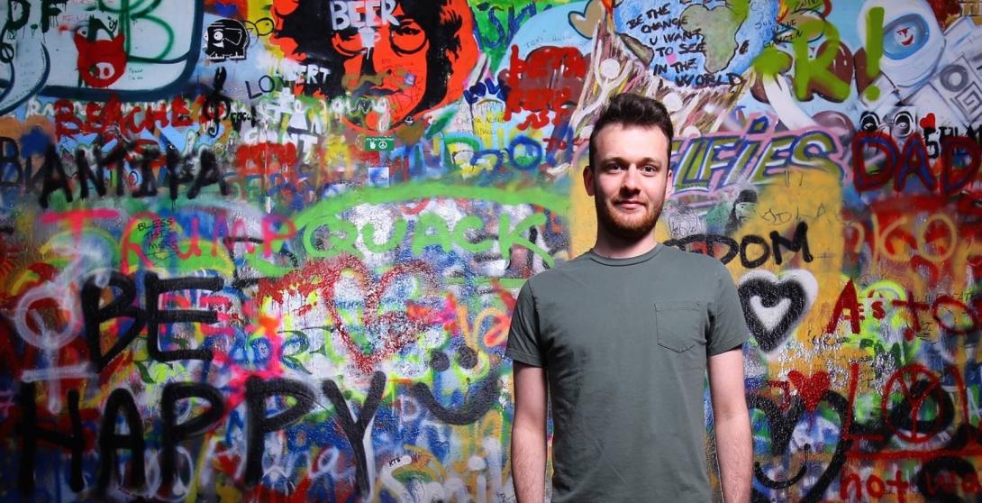 Ben Miller stands in front of a grafitti wall