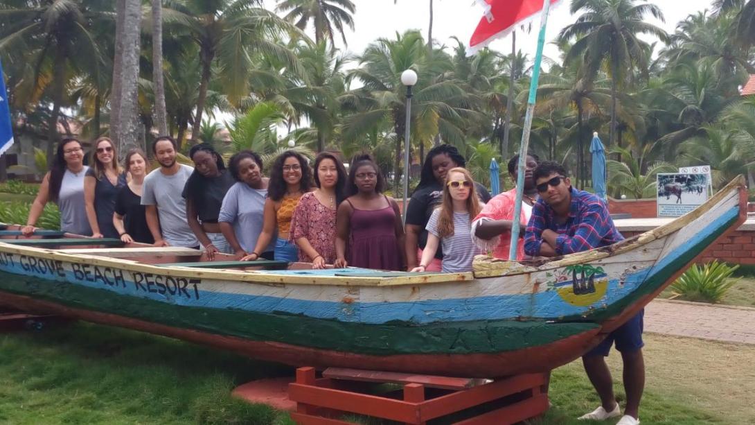 Students stand behind a boat that is on land