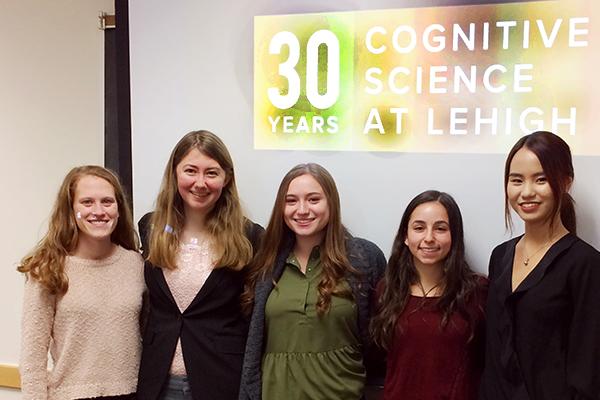 Students stand in front of a projector screen that reads "30 years Cognitive Science at Lehigh"