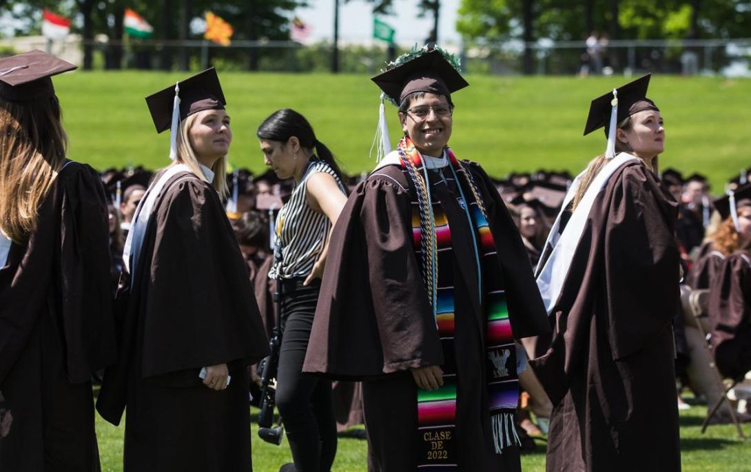 Steven Escobar-Mendez smiles at the camera wearing full graduation regalia 