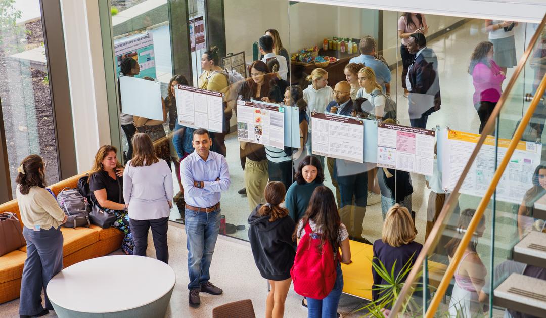 Research symposium in the HST building at Lehigh. People mingle below with posters on a wall.