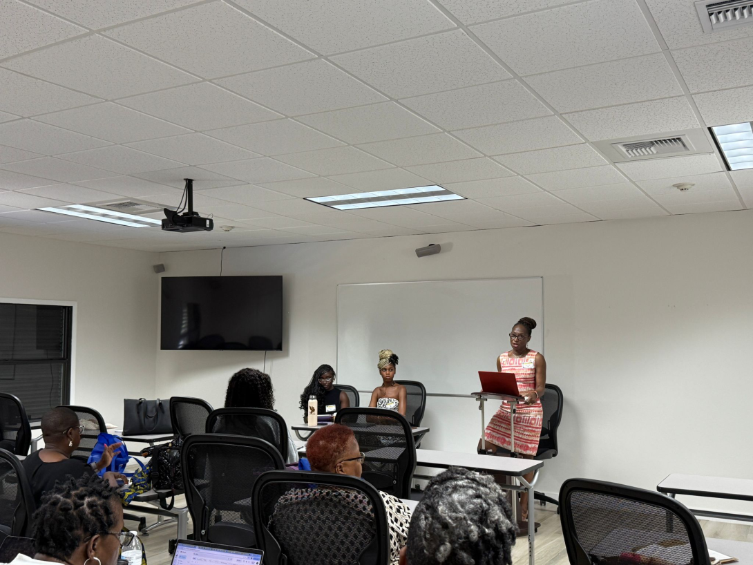 Simone A James Alexander stands at a podium in a classroom to introduce students on a panel. 