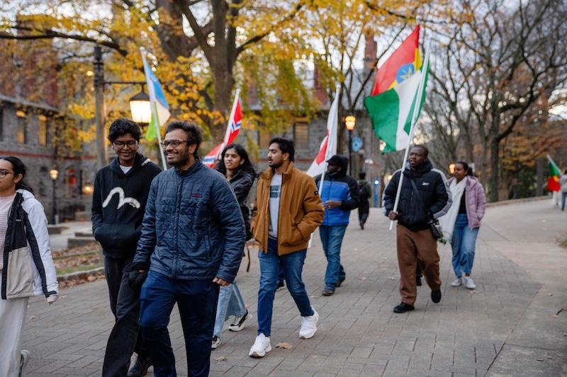Lehigh students walk down the main street with flags from all around the world