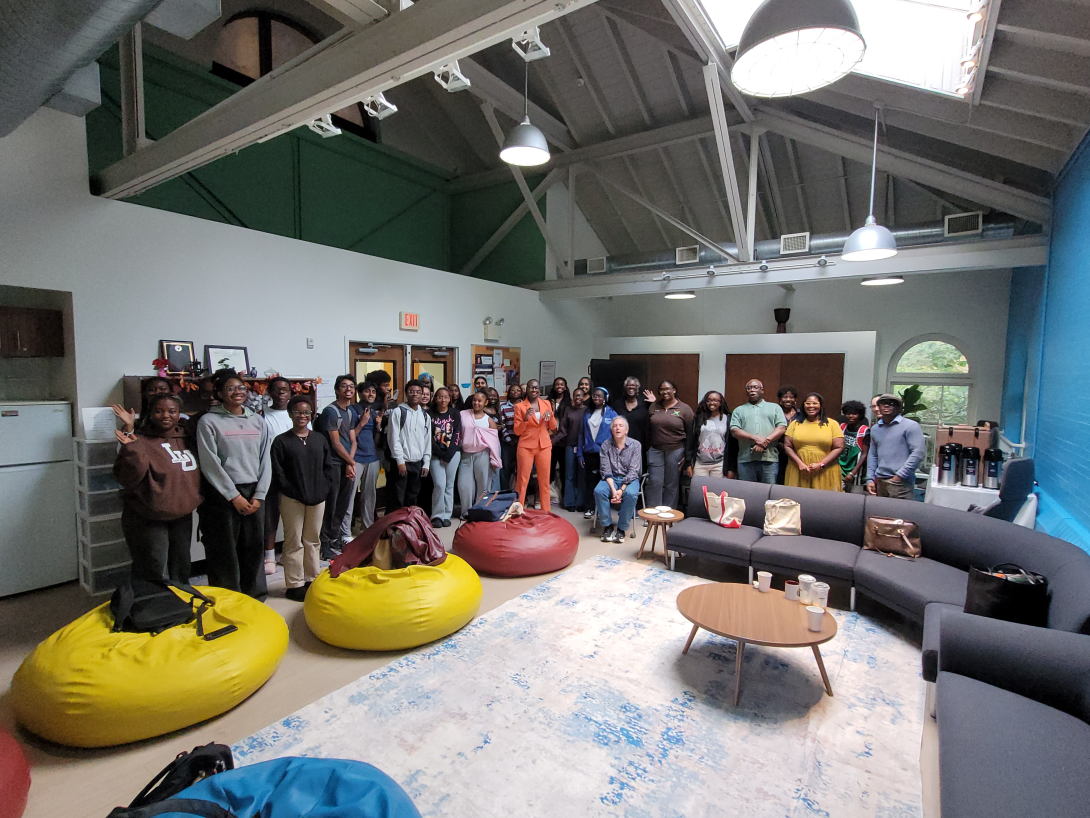 Students and faculty gather in a room for a group photo.